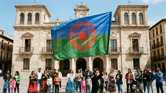 bandera azul y verde con rueda roja ondeando ante un ayuntamiento español durante el Día del Pueblo Gitano