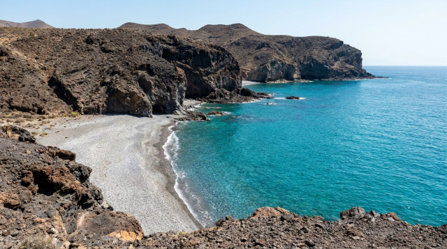 Vista panorámica de la Playa de los Muertos en Almería, mostrando el contraste entre el azul turquesa del mar y los acantilados volcánicos de las mejores playas vírgenes de España