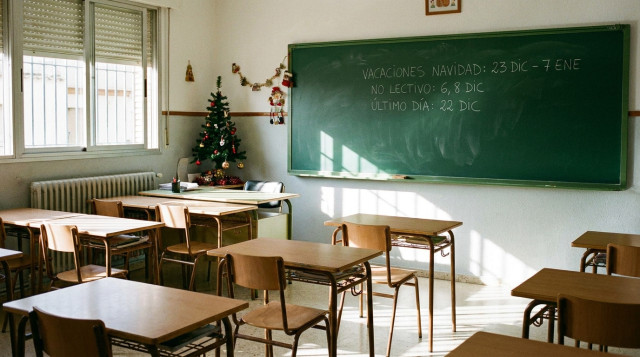 Aulas vacías con pupitres y una pizarra con notas escolares sobre el calendario escolar de diciembre