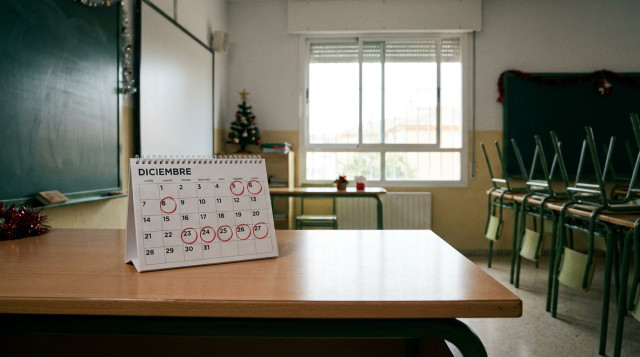 Aula escolar vacía con un calendario de mesa señalando las fechas de diciembre y las vacaciones de Navidad