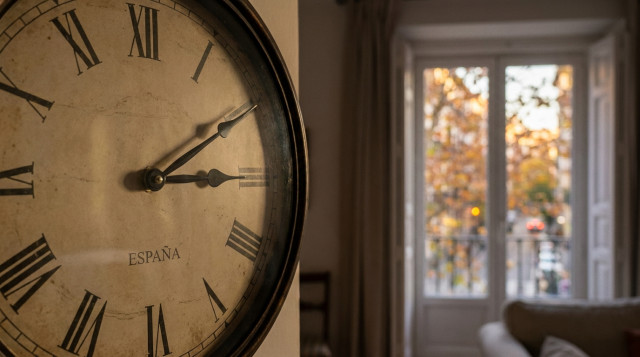primer plano de reloj de manecillas marcando el cambio de hora de invierno en España sobre fondo desenfocado