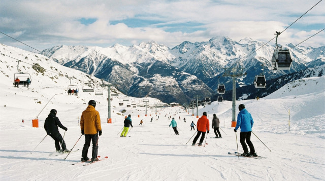 esquiadores en una pista de nieve de los Pirineos con remontes y montañas nevadas al fondo