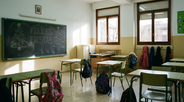 Aulas escolares vacías con adornos navideños sutiles en la pizarra y mochilas descansando antes de las vacaciones de invierno