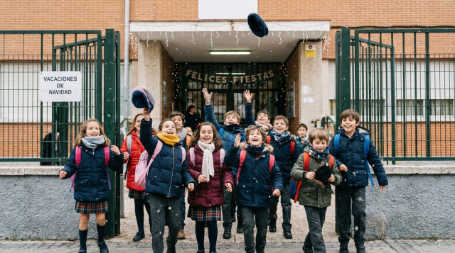 Alumnos saliendo del colegio en invierno con mochilas escolares anunciando las vacaciones escolares de Navidad