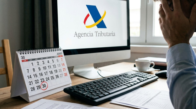 Un primer plano de un teclado de ordenador junto a un calendario de mesa donde el día 30 de junio está marcado en rojo, con la pantalla mostrando el logotipo de la Agencia Tributar