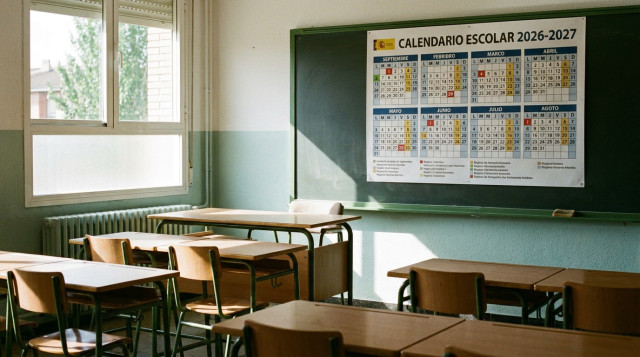Aula de colegio de primaria en España con pupitres vacíos y un calendario escolar 2026-2027 colgado en la pared al inicio del curso