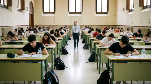 Estudiantes de Bachillerato en España realizando el examen de la nueva Selectividad en un aula universitaria con bolígrafos y hojas de examen
