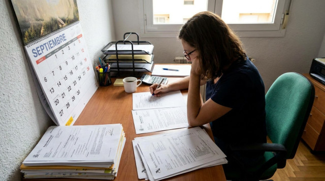 persona revisando un calendario administrativo y documentos oficiales de la Seguridad Social y Hacienda en una mesa de trabajo