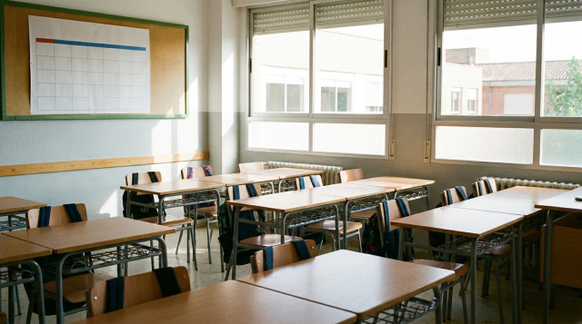 Aulas escolares vacías con pupitres ordenados y mochilas listas para el inicio del calendario escolar en España