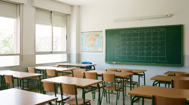 Aula escolar luminosa y organizada con pupitres y pizarra preparada para el calendario escolar del nuevo curso