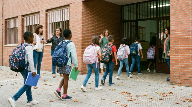 Alumnos entrando a un colegio con mochilas y material escolar al inicio del curso lectivo en España