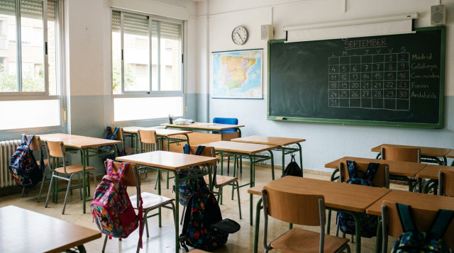 Aula escolar luminosa con mochilas y pupitres listos para el calendario escolar en un colegio de Espana
