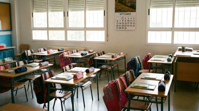 Aulas escolares preparadas con pupitres y mochilas infantiles para el inicio del calendario escolar de septiembre en España