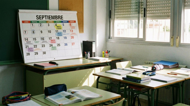 Aulas escolares preparadas con material didactico y calendario escolar de septiembre abierto en la mesa del profesor