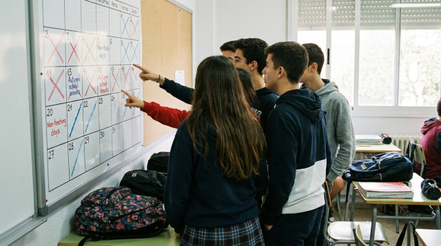 Estudiantes en un aula escolar consultando el calendario escolar con fechas de días no lectivos marcadas