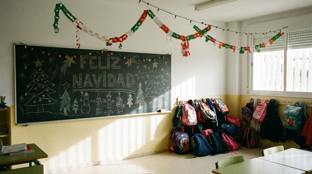 Aulas vacías de un colegio con adornos navideños infantiles en la pizarra y mochilas escolares guardadas