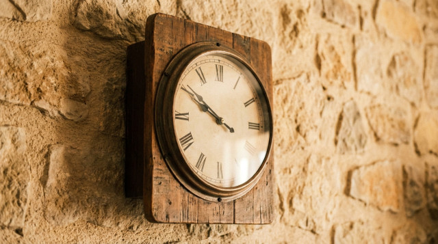 primer plano de un reloj analógico de pared con las manecillas retrocediendo para ilustrar el cambio de hora de otoño