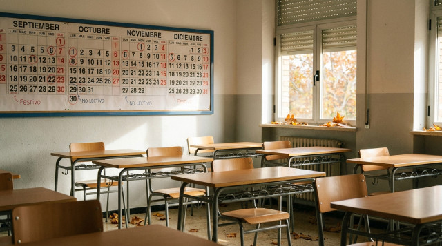 aula escolar vacía en otoño con pupitres ordenados y un calendario en la pared con días no lectivos señalados