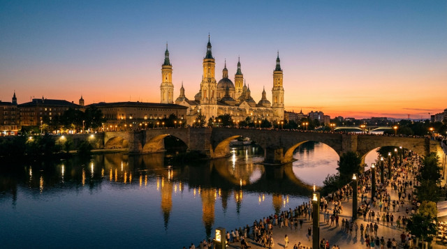 Vista panorámica de la Basílica del Pilar en Zaragoza iluminada al atardecer junto al río Ebro durante el puente festivo