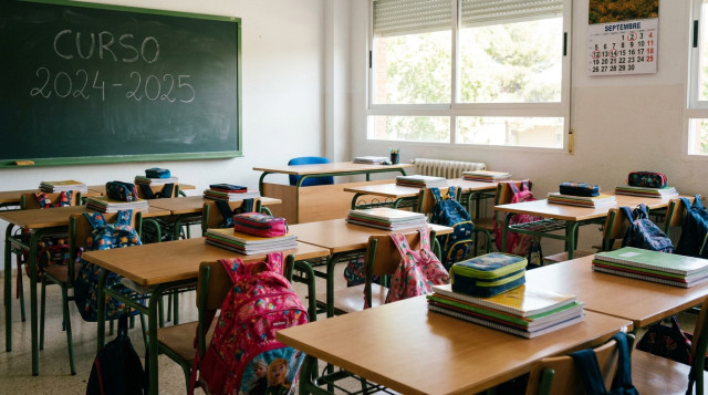 Aula escolar con pupitres ordenados, mochilas y libros preparados para el inicio de las clases de la vuelta al cole
